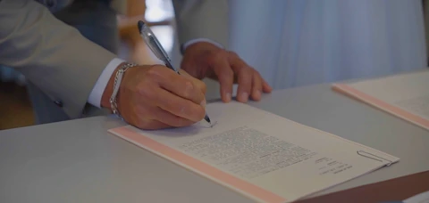 Les mains du marié signant le registre de la cérémonie.